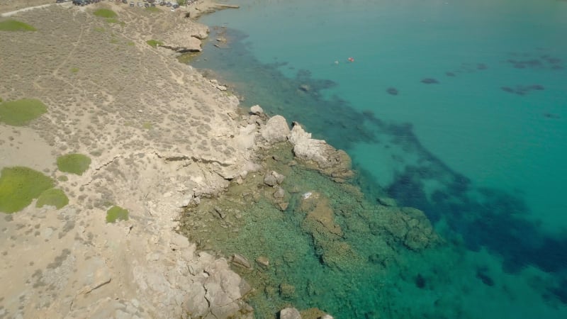 Aerial view of beach shore with rocks and very calm water.