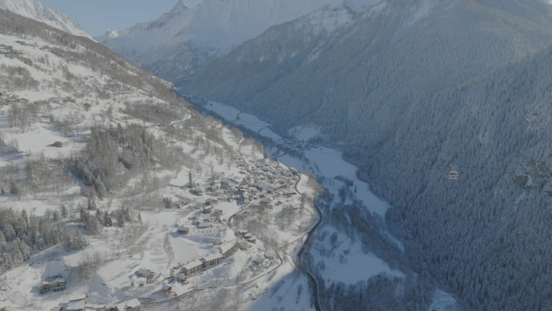 Tracking the cable car lift between ski villages La Plagne and Les Arcs, France with the view of trees and snow-covered mountains