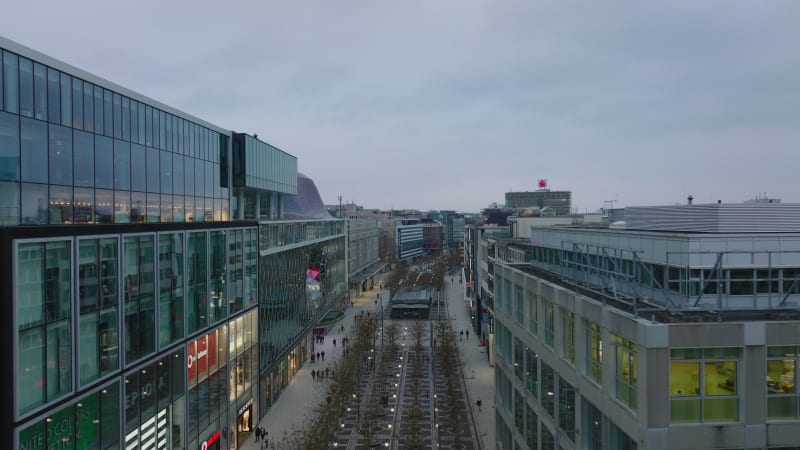 Forwards fly above wide shopping boulevard Zeil. People walking on pedestrian zone with rows of trees in middle. Frankfurt am Main, Germany