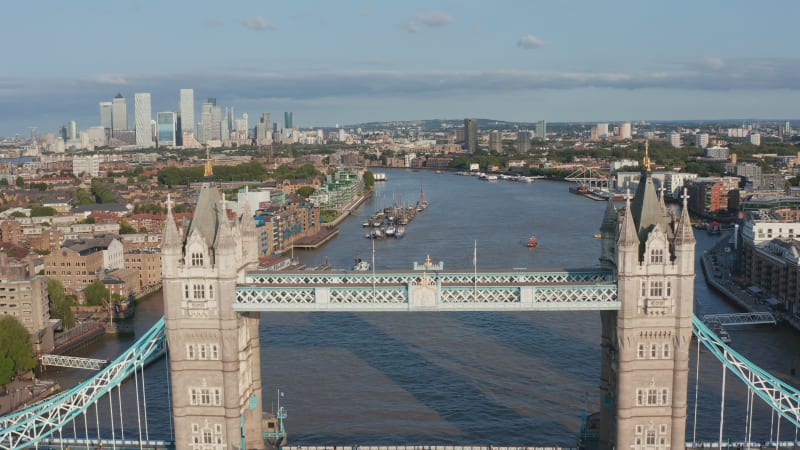 Backwards reveal of old Tower Bridge spanning River Thames. Heavy traffic on historic landmark in afternoon rush hour. London, UK