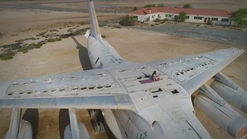 Aerial view woman doing exercise in the top of cargo airplane.