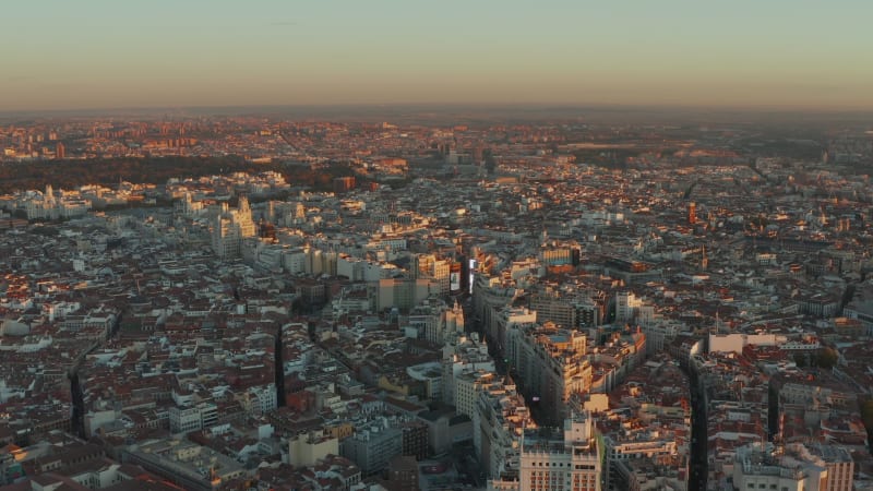 Backwards fly above city centre. Wide panoramic aerial footage of town in sunset time.