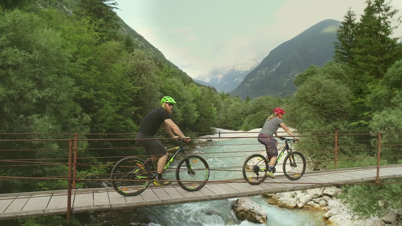 Aerial view of couple crossing a wooden bridge on bicycles.