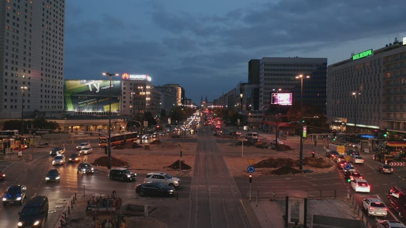 Evening traffic in city centre. Cars driving through large roundabout crossed by tram tracks. Busy streets at twilight. Warsaw, Poland