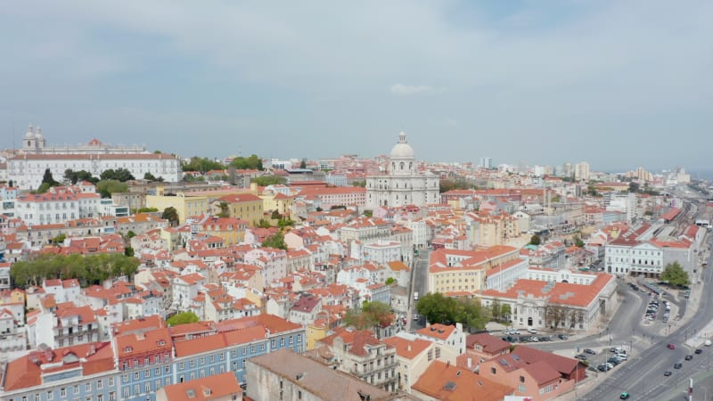 Aerial wide dolly in view of colorful traditional old houses and church on the hills urban city center of Lisbon, Portugal