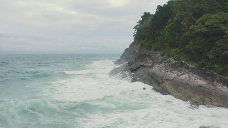 Rough waves crashing on the rocky cliff shore