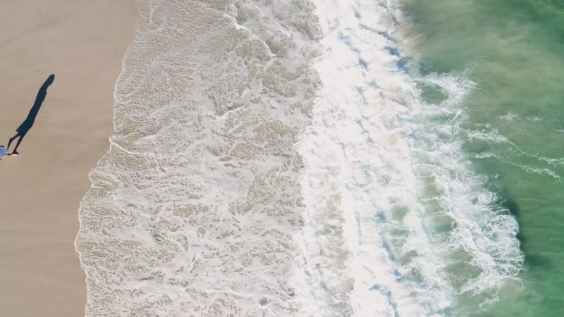 Aerial view of woman standing on white beach, Cape Town, South Africa.