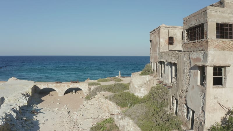 Aerial Dolly along Old Abandoned Factory Building at Beach on Milos Island, Greece