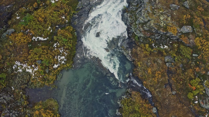 Fast moving clear water stream and moss covered rocks in Norway.