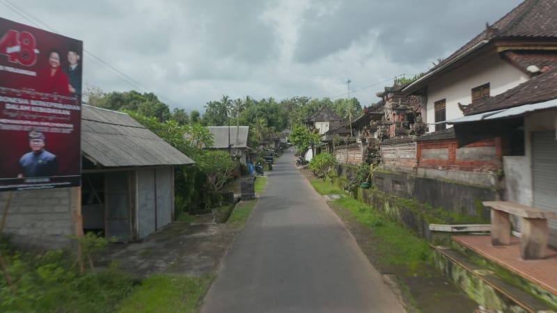 Low flying aerial pov shot down the traditional street in the residential community in Bali, Indonesia