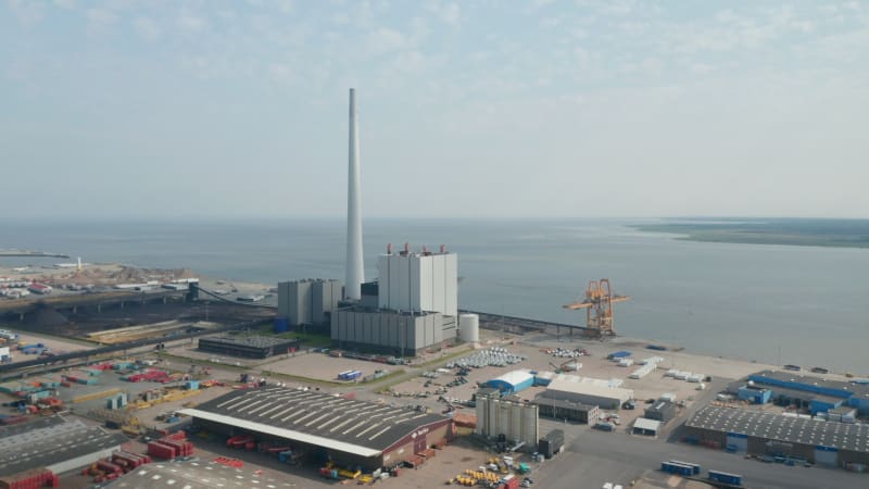 Birds eye slowly rotating around the chimney of Steelcon power station in Esbjerg, Denmark. Aerial drone view of coal and oil fueled power plant with the tallest chimney of Scandinavia