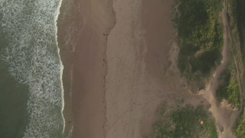 Aerial view of waves breaking on the beach in Cornwall, United Kingdom.