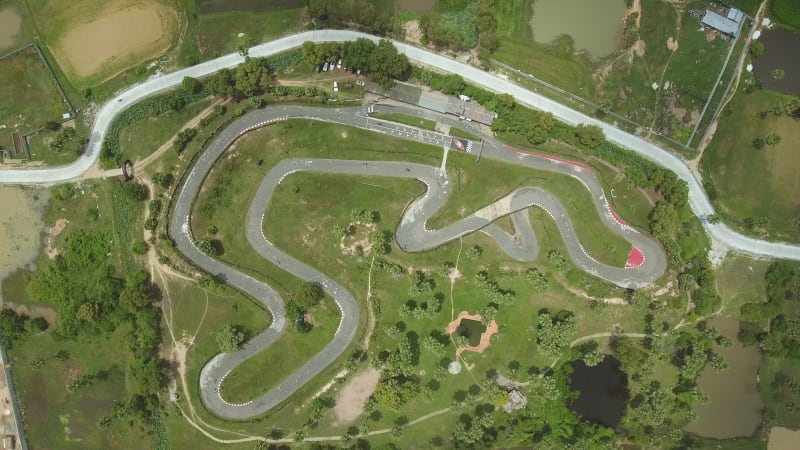 Faraway aerial view of a group driving kart on a speedway.