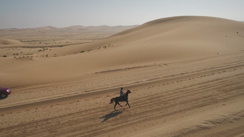 Aerial view of one person riding horse in the desert of Al Khatim.