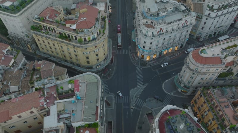 High angle view of road intersection surrounded by luxury palaces in city centre. Aerial descending footage of buildings with rooftop terraces. Rome, Italy