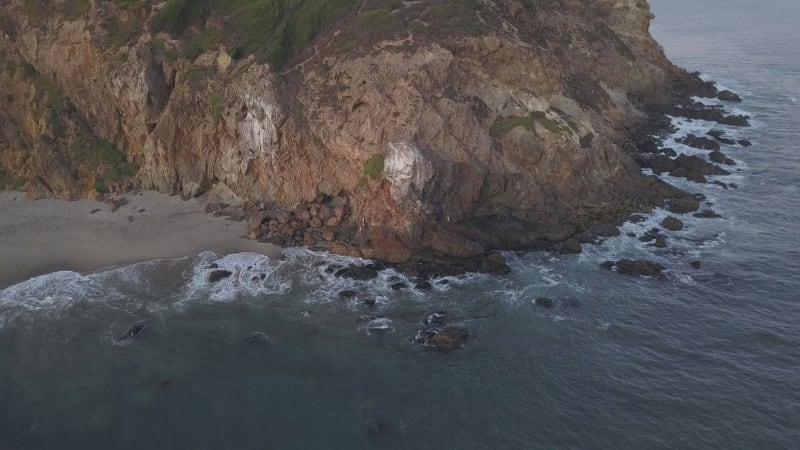 AERIAL: flight over Malibu, California view of beach Shore Line Pacific ocean at sunset with mountain cliff