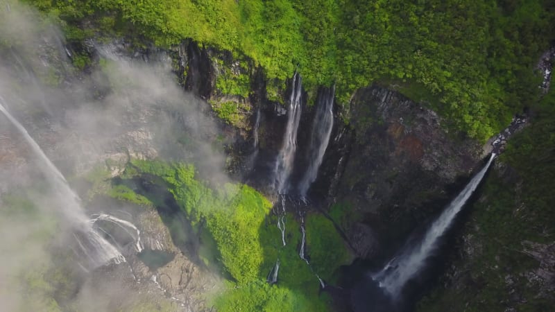 Aerial view above waterfall surrounded by jungle.