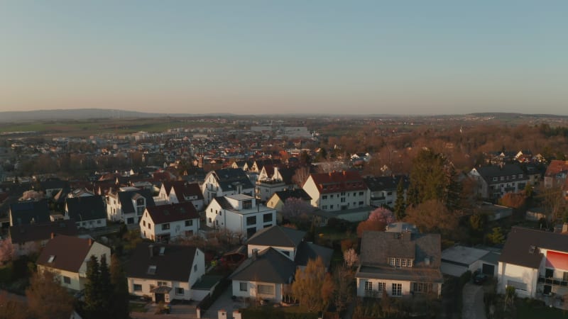 Panoramic aerial view of small town and surrounding landscape. White gables of houses lit by bright evening sun. Bad Vilbel, Germany.