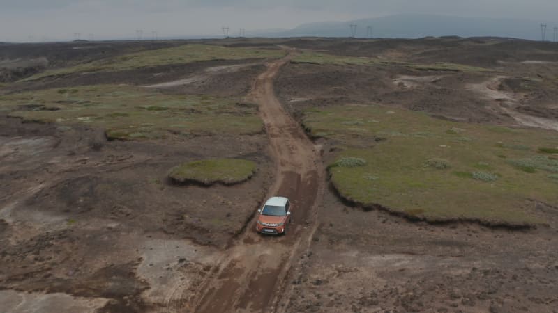 Aerial view tracking car moving on wild road in Iceland. Forward flight on surreal icelandic landscape. Adventure roadtrip of a car offroad