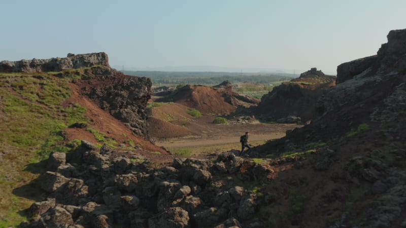 birds eye drone view man tourist running pathway in desert rock formation panorama in Iceland. Aerial view hiker exploring wilderness in Iceland