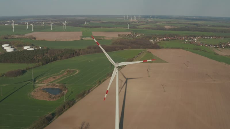 Close up shot of wind Turbine, Mill rotating by the force of the Wind Generating Renewable Energy in a Green Ecologic way for the Planet over beautiful Green Agriculture field