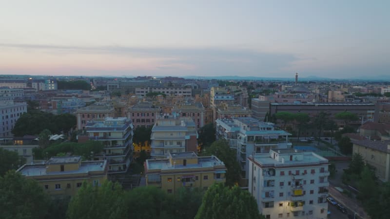 Slider of urban borough at twilight. Aerial view apartment buildings and green trees in park. Rome, Italy