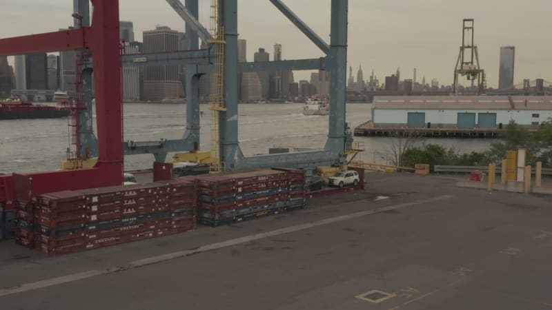 Flying through big blue cargo industrial crane revealing New York City skyline and east river on a cloudy day