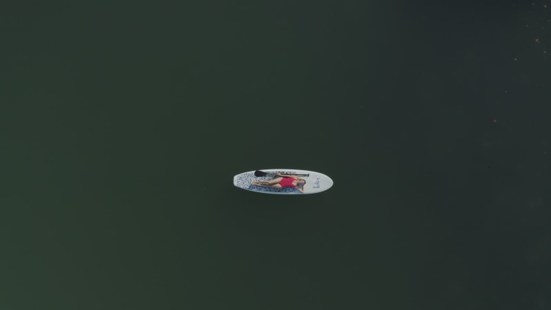 Aerial view of a blonde woman laying on a surfboard, Mauritius.