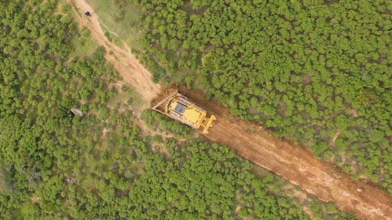 Aerial view of bulldozer deforestating trees in mountains of Marbella.