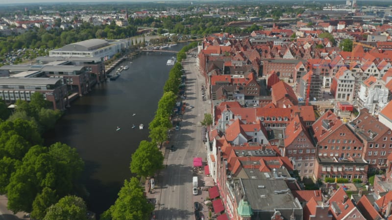 Aerial sliding footage of historic brick town houses, wide riverside street and Trave river. Luebeck, Schleswig-Holstein, Germany