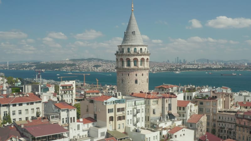 Ancient Galata Tower in Center of Istanbul on clear Blue Sky Day, Crane Shot up revealing Bosphorus River