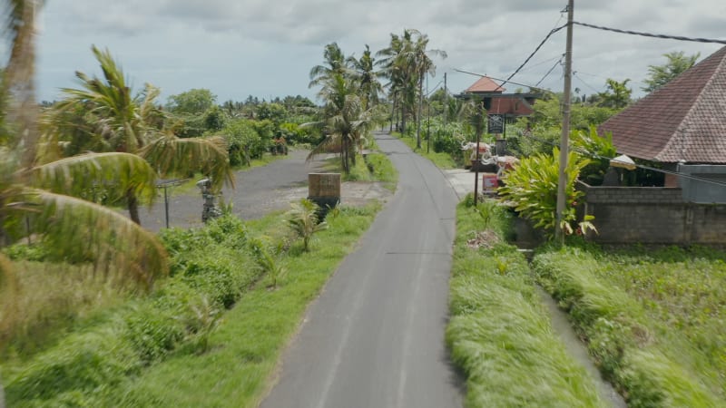 Low flying aerial dolly street view shot of traditional restaurant on the side of the road in Bali, Indonesia