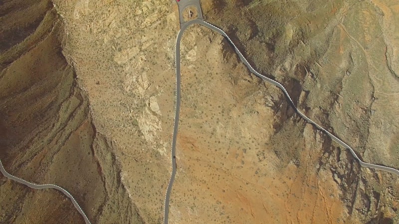 Aerial view of a car driving on a winding mountain road.