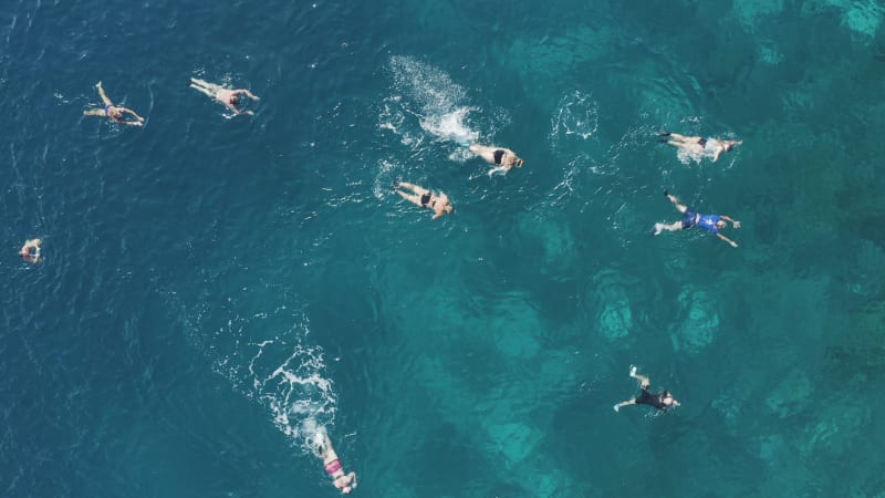 View from above swimmers snorkeling in clear blue water and coral reef in Philippines