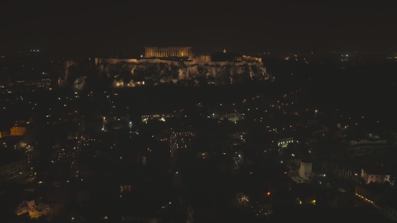 Aerial view of the parthenon temple on acropolis hill at night in Athens.