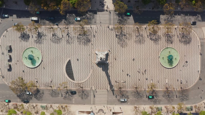 Aerial overhead top down birds eye view of people walking around large public square with water fountains in Lisbon city center