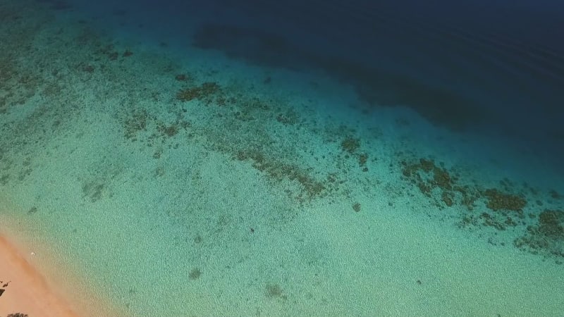 Aerial view of a man swimming alone on the paradisiacal beach on Koh Rok Yai island.