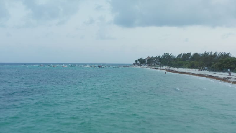 Drone approaching moored wooden boats on the shoreline of Caribbean Sea at Playa del Carmen, Mexico