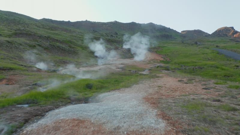 Birds eye flying toward geyser geothermal area with steaming craters in Iceland. Aerial drone view of spectacular fumaroles