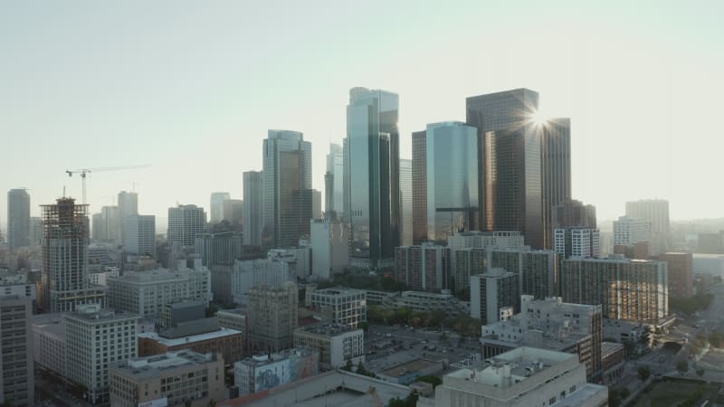 Flying towards Downtown Los Angeles, California Skyline with look at houses and street traffic at beautiful blue sky and sunny day