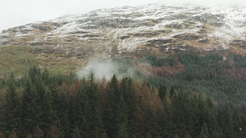 Aerial view of the Scottish mountains with fog rising from the tree tops