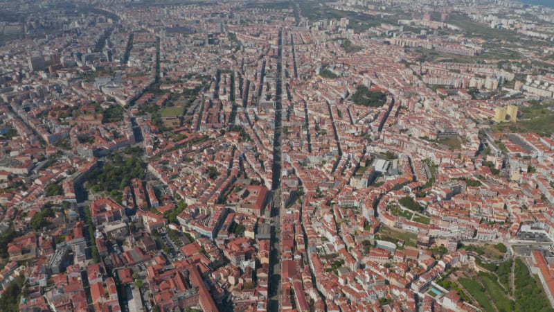 High angle view of rooftops cityscape. Long straight street from slowly forward flying drone. Lisbon, capital of Portugal.