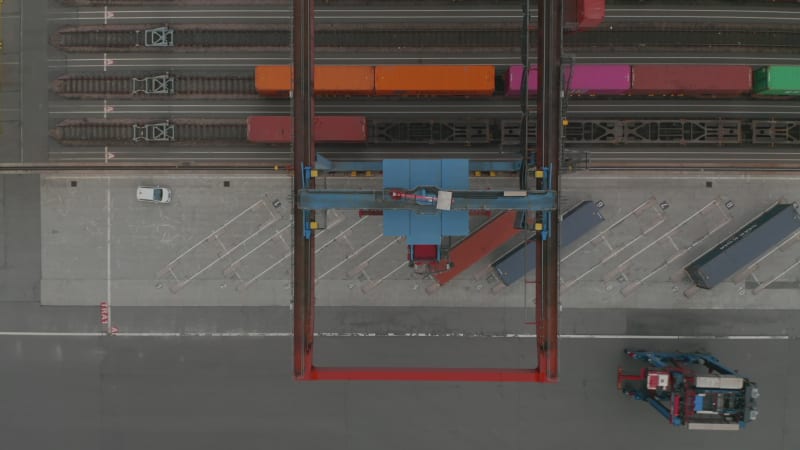 Birds eye overhead aerial view of cargo crane moving cargo containers in industrial seaport in Hamburg