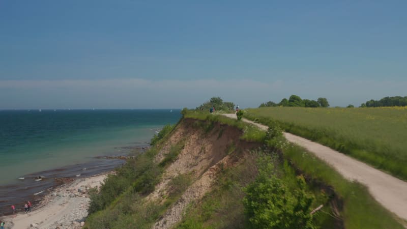 Peaceful coastline scenery, aerial drone flying above foot walk path with blue turquoise Baltic sea water on background, forward, day