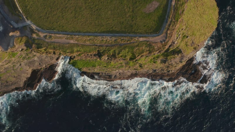 Aerial birds eye overhead top down view of waves crashing to coastal cliff. Amazing natural scenery. Cliffs of Moher, Ireland