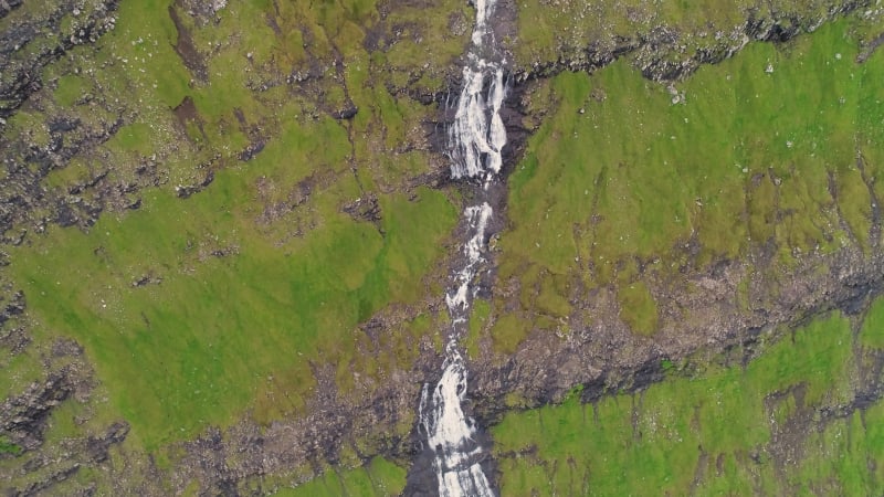 Aerial view of breathtaking waterfall crossing rock mountain.