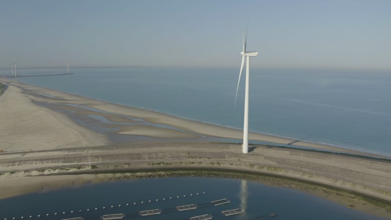 Wind turbine on a sandy beach next to the mussel farm facilities