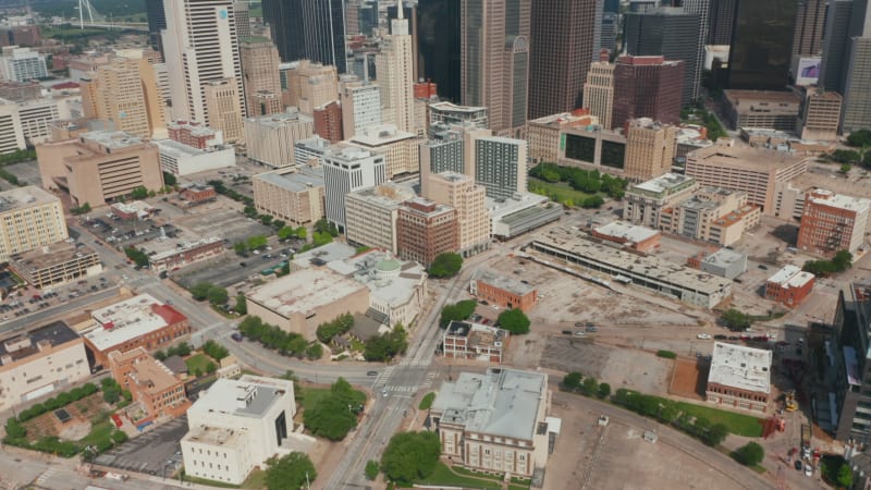 Tilt up reveal of modern downtown skyscrapers. Forwards fly above streets of city. Dallas, Texas, US