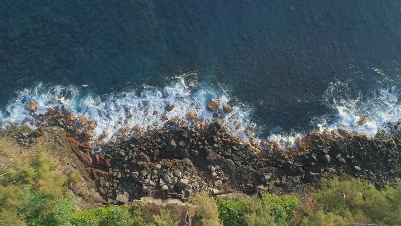 Birds Eye View of a Rocky Beach with Waves Crashing Against The Rocks