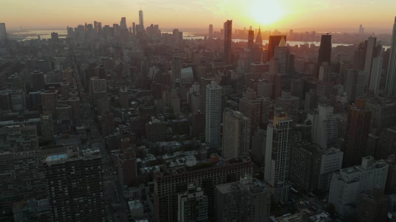 Backwards fly above city. Aerial view of cityscape against golden sunset. Manhattan, New York City, USA